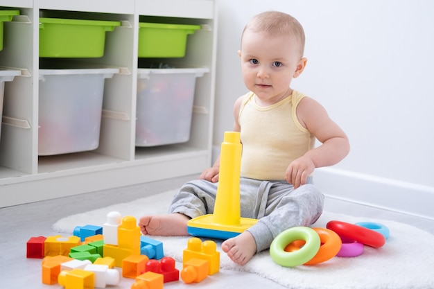 Linda niña jugando en una pirámide colorida en el suelo en casa Desarrollo de la primera infancia