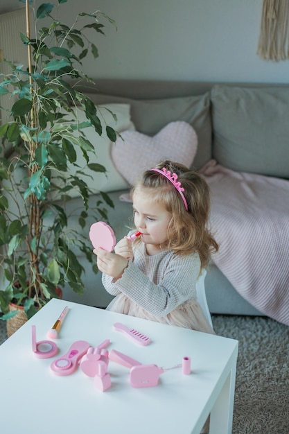 Linda niña está jugando en un salón de belleza hermosa niña de 3 años hace  maquillaje con cosméticos para niños en casa