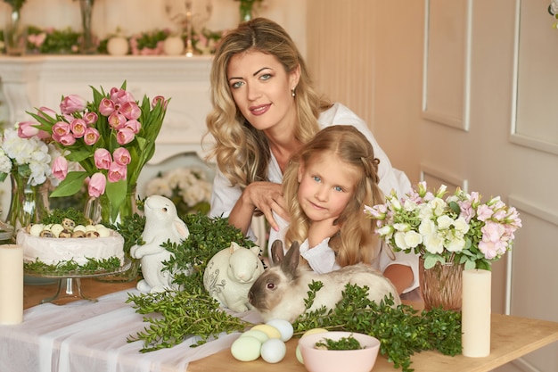 Linda niña y madre jugando con conejo