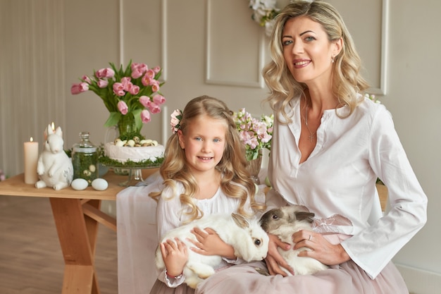 Linda niña y madre jugando con conejo