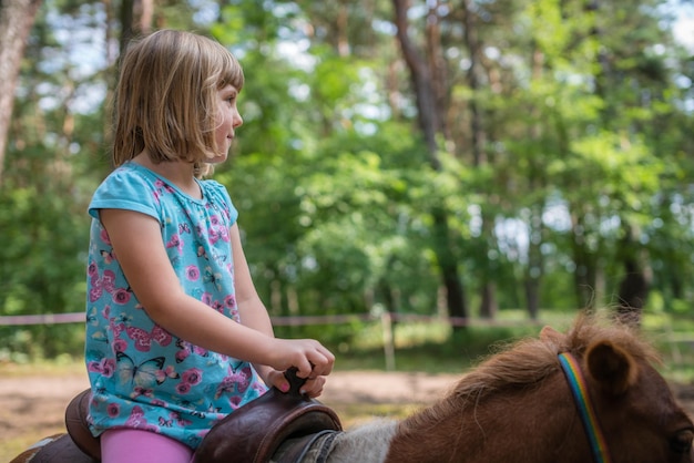 Linda niña montando en un pony