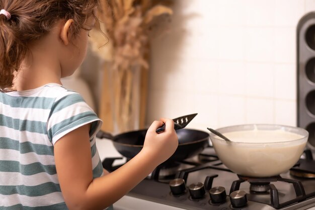 Foto linda niña niño en la cocina en casa haciendo panqueques concepto de cocina para niños