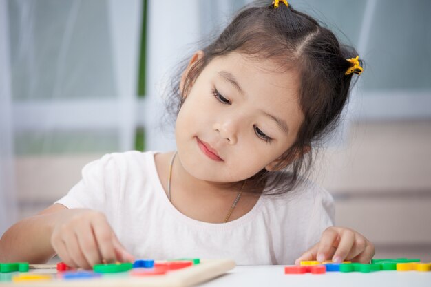 Linda niña niño divirtiéndose para jugar y aprender alfabetos magnéticos a bordo en la habitación