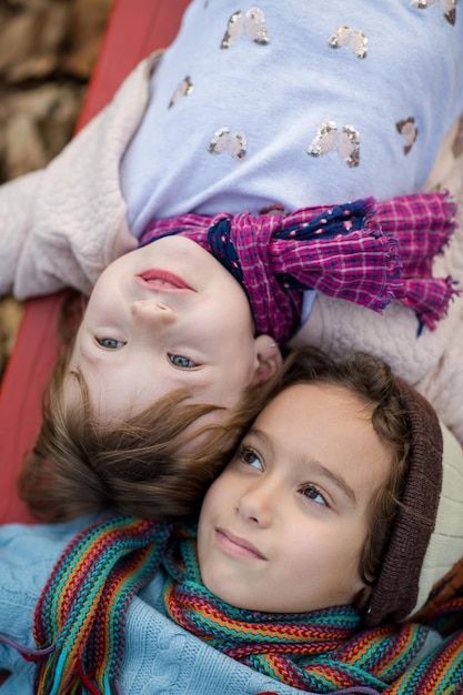 linda niña y niño en el parque infantil divirtiéndose y alegrándose mientras juega en el patio de recreo en el día nublado de otoño