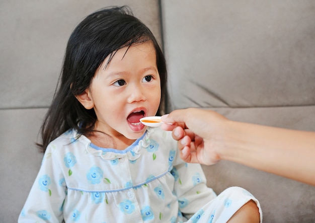 Linda niña niño recibiendo píldora en casa