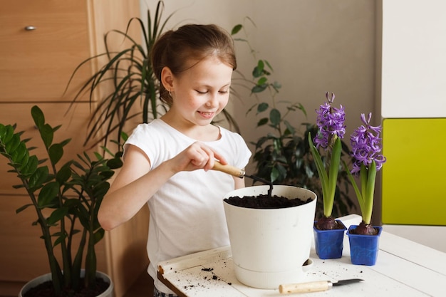 Linda niña ocupada con el cultivo de plantas caseras