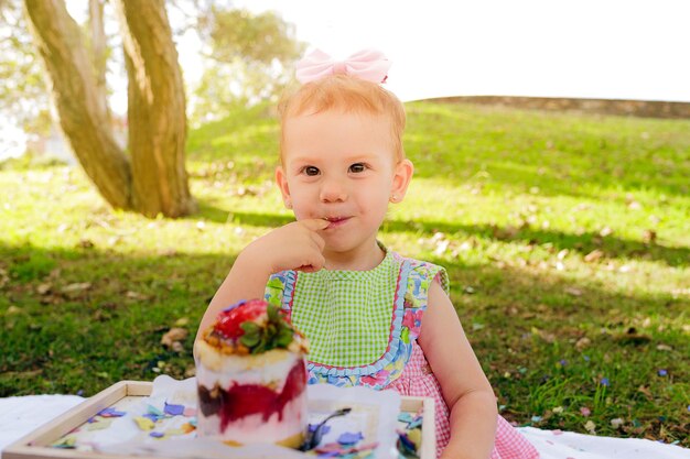 Linda niña pelirroja durante un picnic en el parque en su segundo cumpleaños