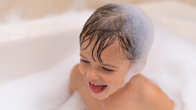 Linda niña pequeña en el baño con espuma de jabón