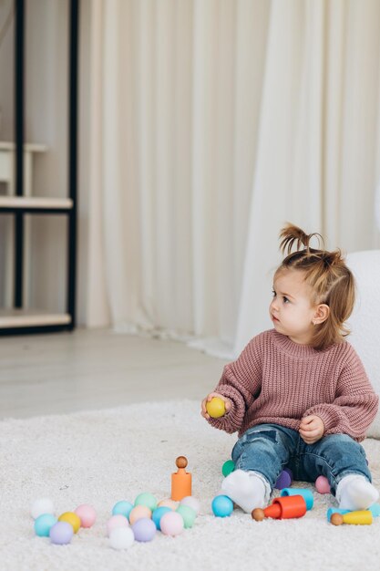 Linda niña pequeña jugando en casa con juguetes de madera ecológicos Niño feliz cortando verduras y frutas con un cuchillo de juguete El niño jugando juegos educativos