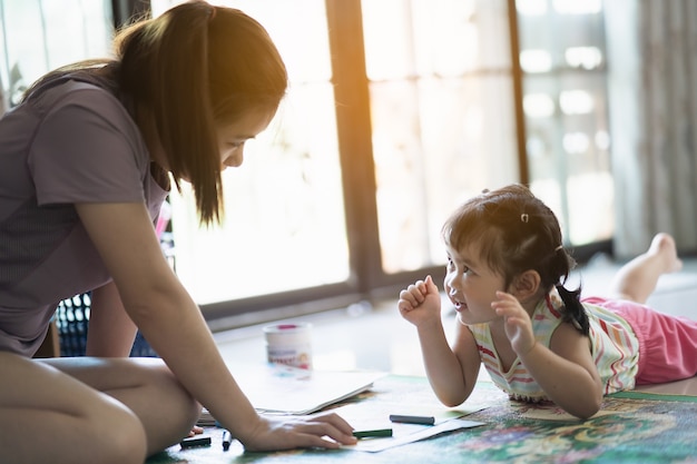 Linda niña pintando con su madre en la casa