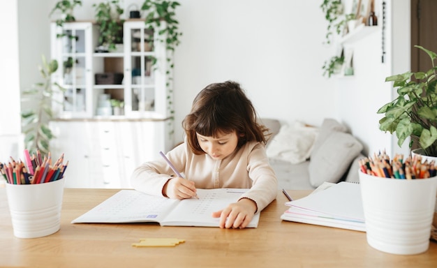 Linda niña preescolar aprendiendo en casa Aprendizaje a distancia de educación en el hogar para niños