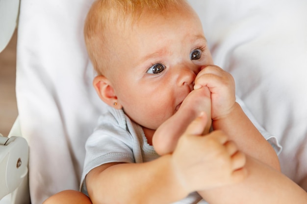 Linda niña recién nacida con cara divertida chupando el dedo del pie sobre fondo blanco Bebé descansando jugando acostado en la silla de alimentación en casa Concepto de niño feliz de maternidad