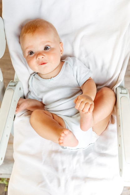 Linda niña recién nacida con cara sonriente mirando a la cámara sobre fondo blanco Bebé descansando jugando acostado en la silla de alimentación en casa Concepto de niño feliz de maternidad