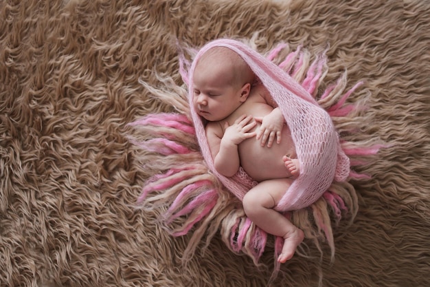 Foto linda niña recién nacida durmiente en una envoltura rosa