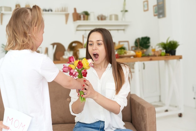 Una linda niña regala flores y felicita a su madre feliz día de la madre o el 8 de marzo