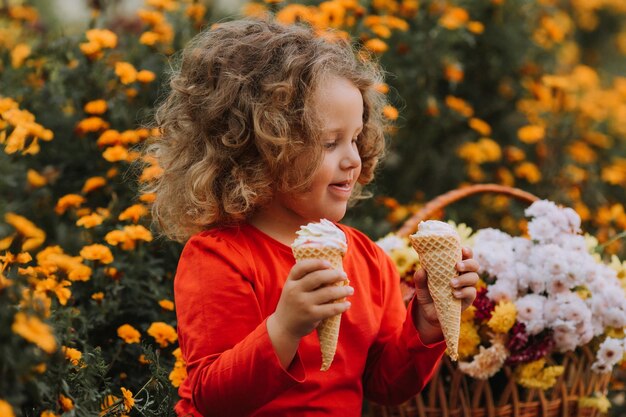 linda niña rizada comiendo helado en el parque tiempo de otoño tarjeta de otoño banner de flores