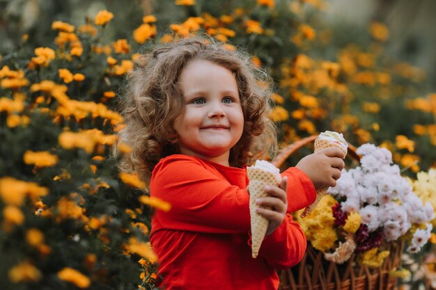 linda niña rizada comiendo helado en el parque tiempo de otoño tarjeta de otoño banner de flores