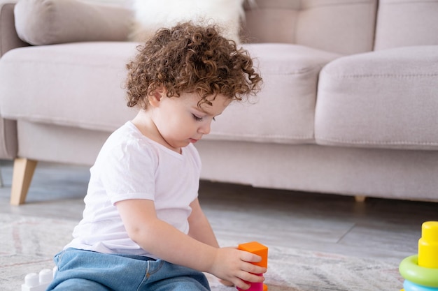 Linda niña rizada jugando con constructor en casa desarrollo infantil temprano