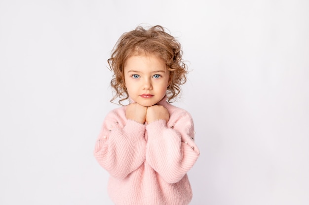 Linda niña en ropa de invierno rosa sobre fondo blanco, espacio para texto