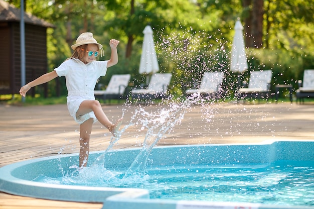 Una linda niña rubia cerca de la piscina.