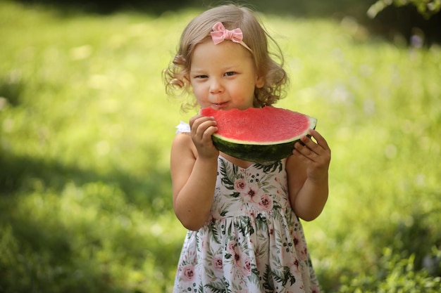 Foto una linda niña rubia come una sandía roja fresca en el verano en la calle