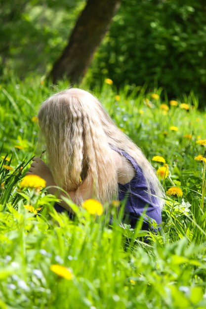 Linda niña rubia en el prado en el parque de verano