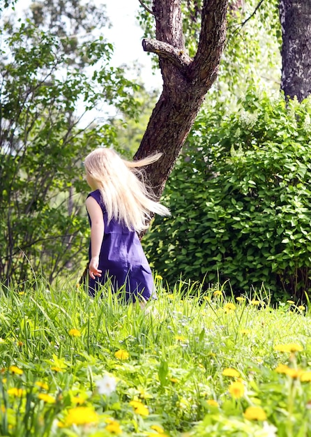 Linda niña rubia en el prado en el parque de verano