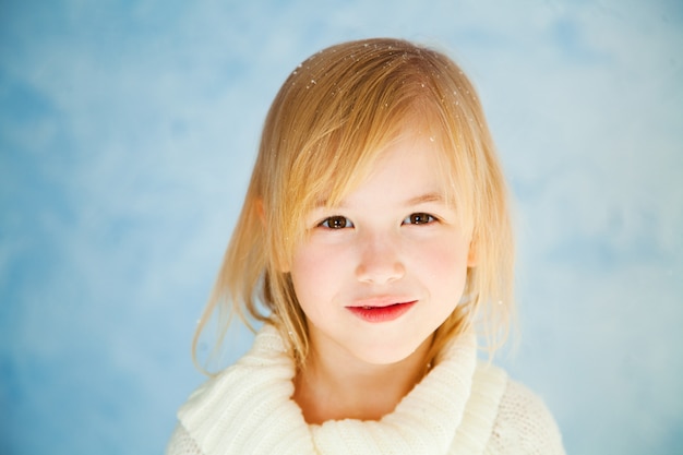 Linda niña rubia sobre el fondo azul