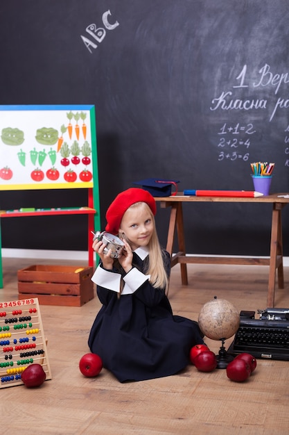 Linda niña rubia en uniforme en el aula