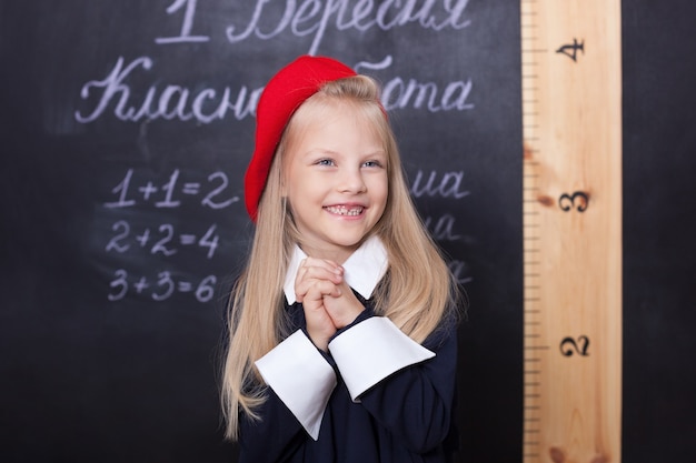 Linda niña rubia en uniforme en el aula