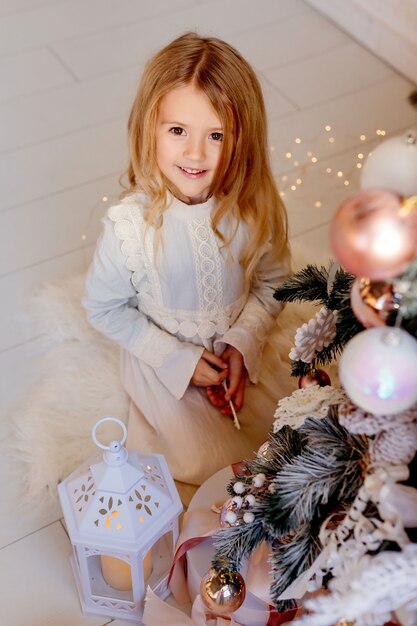 Linda niña rubia vestida cerca del árbol de Navidad