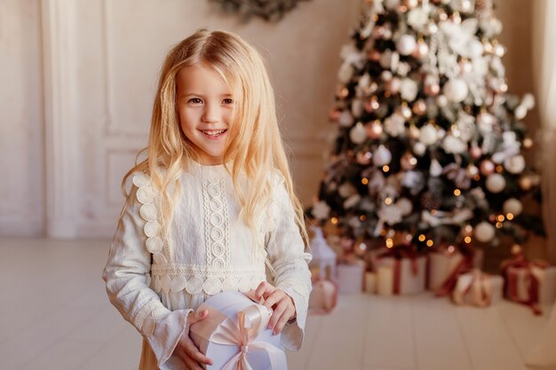 Linda niña rubia vestida cerca del árbol de Navidad