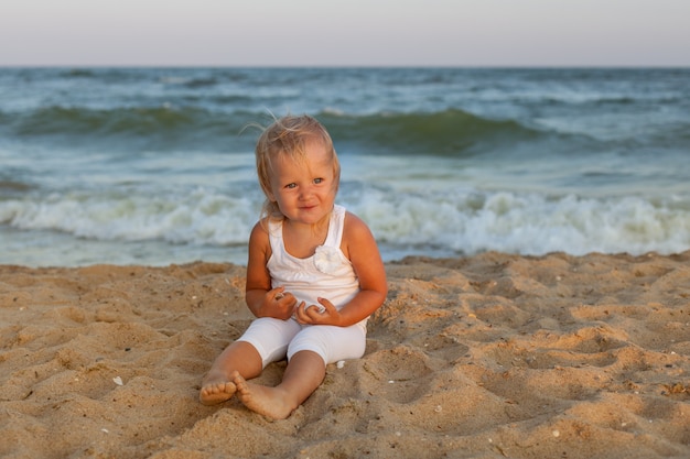 Linda niña sentada en la orilla del mar