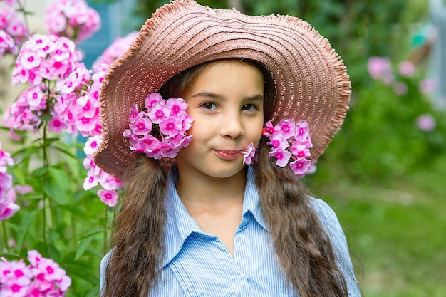 Linda niña con sombrero con flores rosas phlox