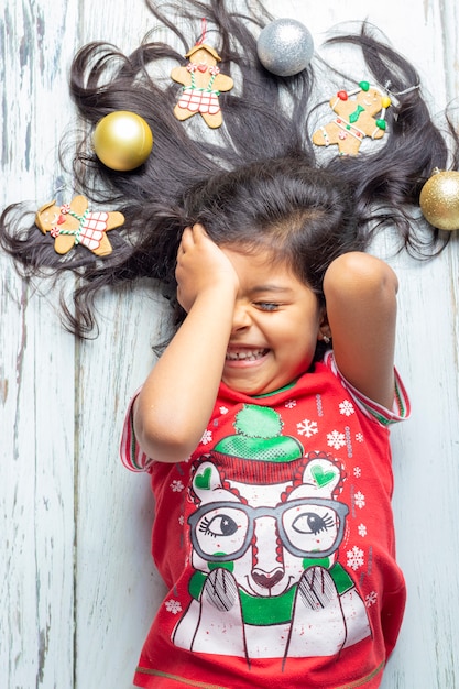 Linda niña sonriente alegre con el pelo decorado de Navidad