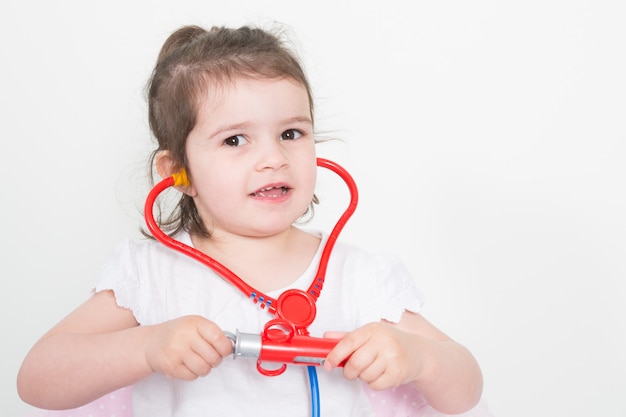 Foto linda niña sonriente jugando enfermera con un estetoscopio