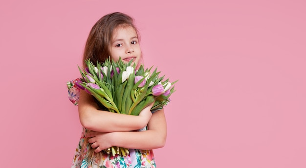 Linda niña sonriente niño sosteniendo ramo de flores de primavera