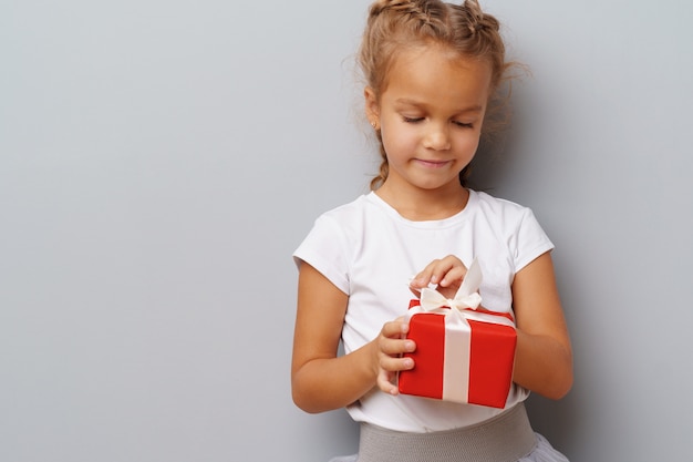 Linda niña sosteniendo una caja de regalo roja en sus manos