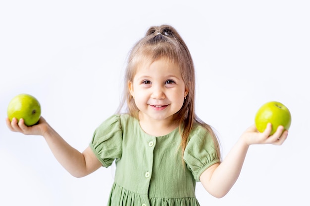 Una linda niña sostiene una gran manzana verde en sus manos Fondo blanco aislado Alimentos saludables para niños o un refrigerio saludable Espacio para texto Fotografía de alta calidad