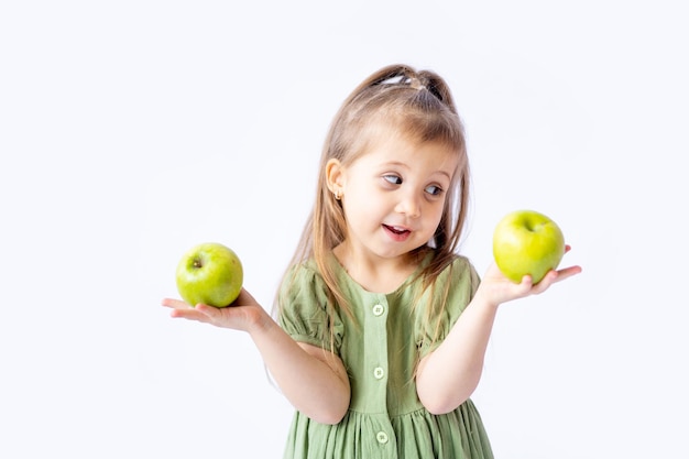 Una linda niña sostiene una gran manzana verde en sus manos Fondo blanco aislado Alimentos saludables para niños o un refrigerio saludable Espacio para texto Fotografía de alta calidad