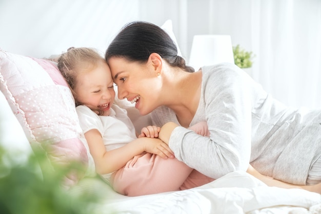 Una linda niña y su madre disfrutan de la mañana soleada. Buen tiempo en casa.