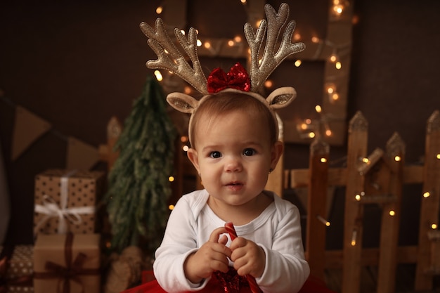 linda niña vestida con un disfraz de Año Nuevo mordisquea una piruleta de Año Nuevo