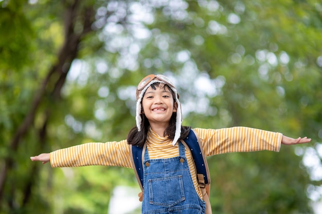 Una linda niña vestida con una gorra y gafas de piloto. El niño sueña con convertirse en piloto.