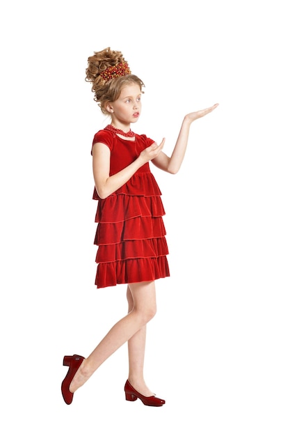 Linda niña en vestido de terciopelo rojo con peinado retro aislado sobre fondo blanco.