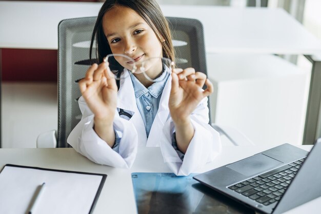 Una linda niñita doctora con una gran bata de laboratorio y un estetoscopio