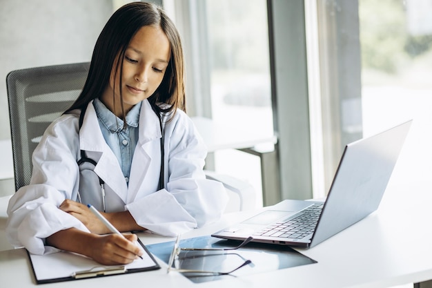 Una linda niñita doctora con una gran bata de laboratorio y un estetoscopio