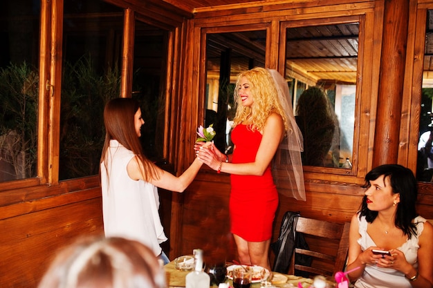 Linda noiva aceita um presente floral de uma dama de honra no restaurante na despedida de solteira