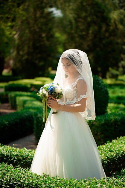 Linda noiva com buquê de flores do casamento, mulher atraente vestido de noiva. Mulher recém-casada feliz. Noiva com casamento maquiagem e penteado. Noiva sorridente. Dia do casamento. Casamento.