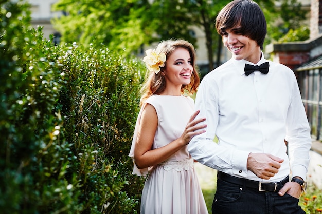 Linda noiva com cabelo longo encaracolado e noivo em pé perto um do outro nas folhas verdes, foto de casamento, dia do casamento, retrato.