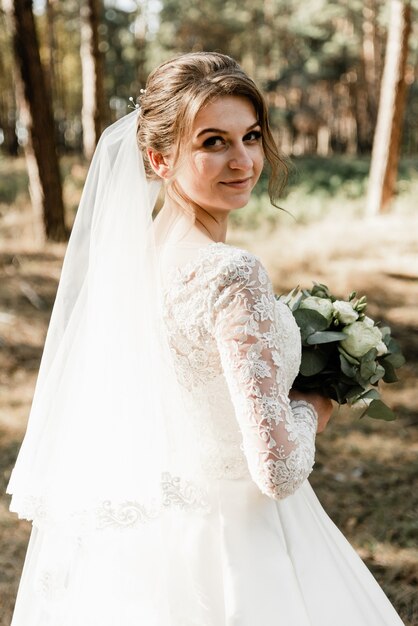 Linda noiva com um buquê nas mãos do lado de fora. noiva com cabelo branco na floresta. retrato da noiva. vestido de noiva elegante. garota em um dia de casamento.